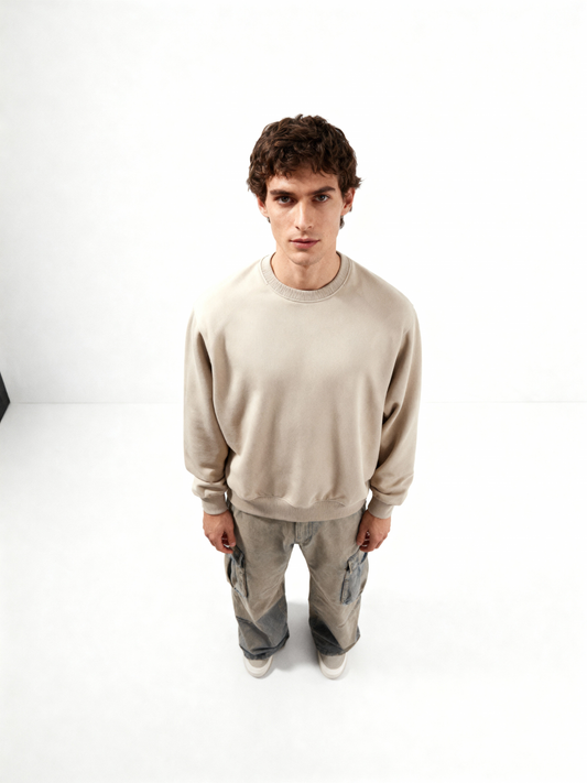 Man wearing a beige sweatshirt and gray pants on a white background