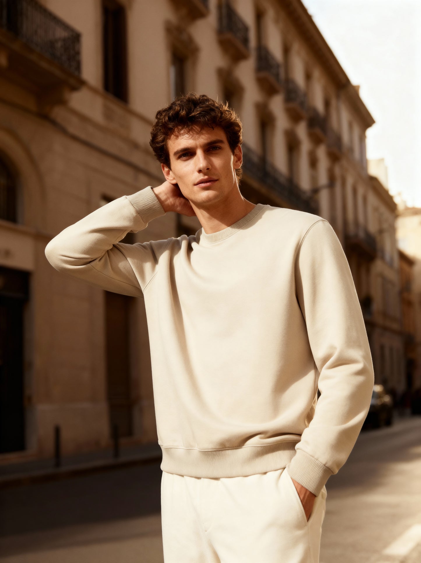 Man wearing a light-colored sweatshirt and pants on a city street.