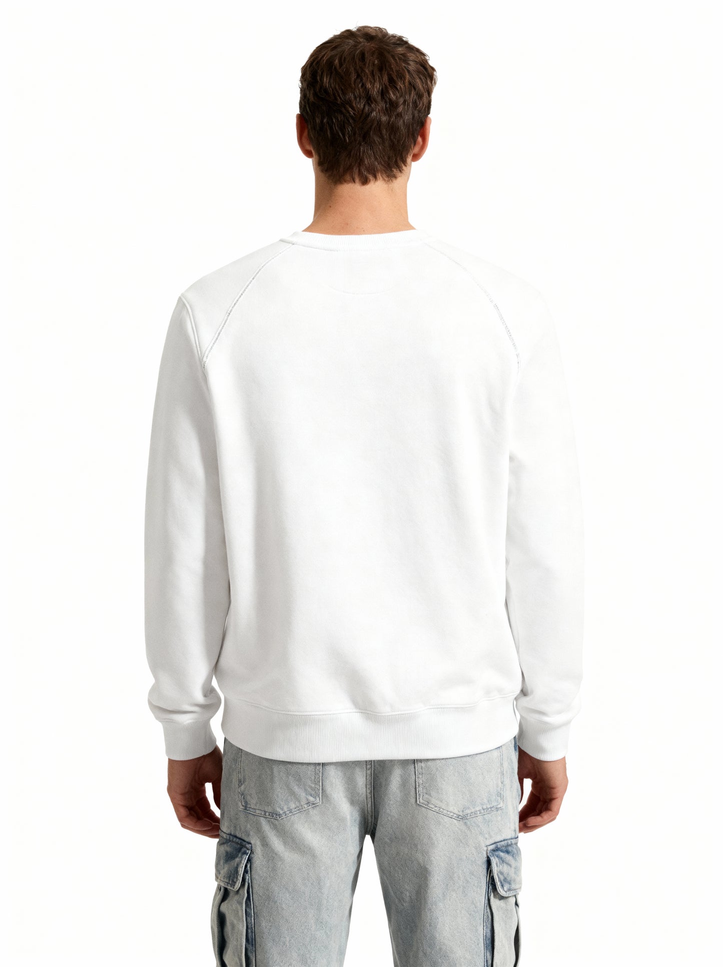 Person wearing a white sweatshirt and light blue jeans on a white background