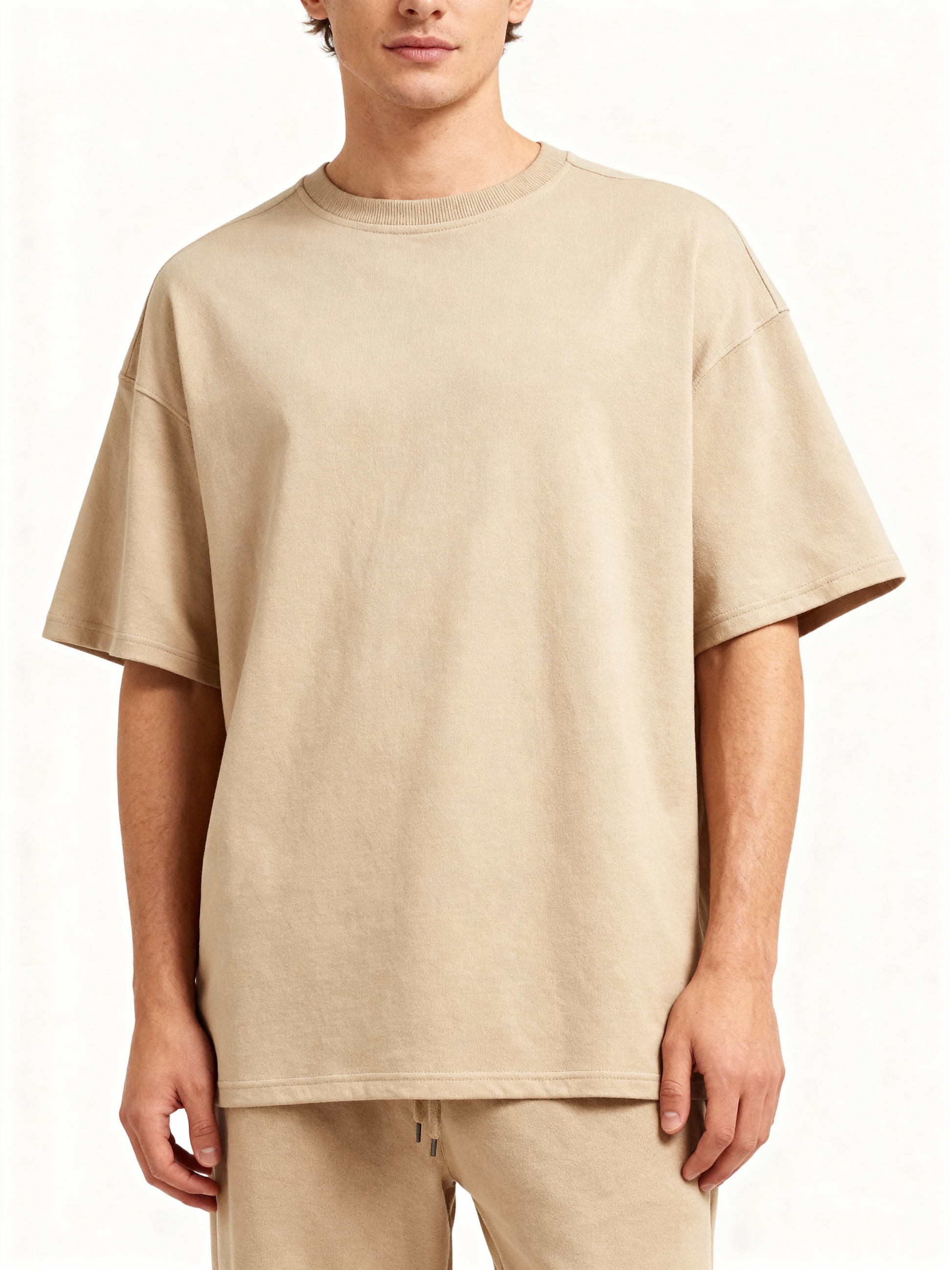 Person wearing a beige oversized t-shirt on a white background