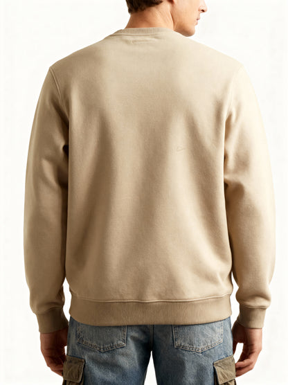 Person wearing a beige sweatshirt and blue jeans on a white background