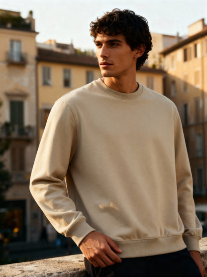 Man wearing a beige sweatshirt standing in an urban setting
