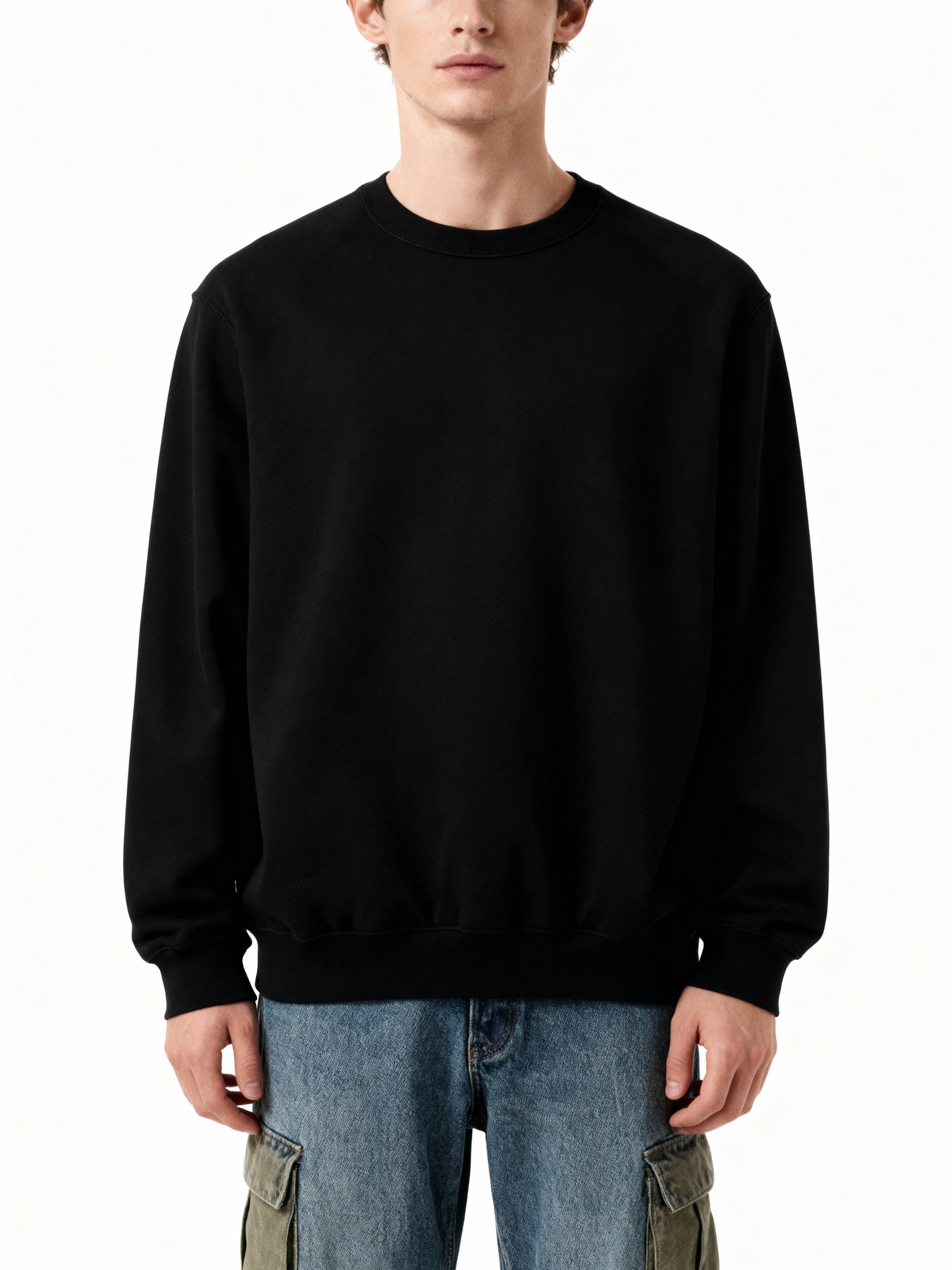 Person wearing a black sweatshirt and blue jeans on a white background