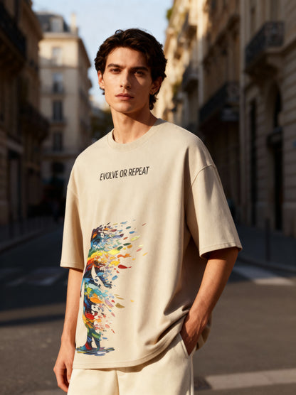 Man wearing a beige t-shirt with a colorful graphic and text on a city street.