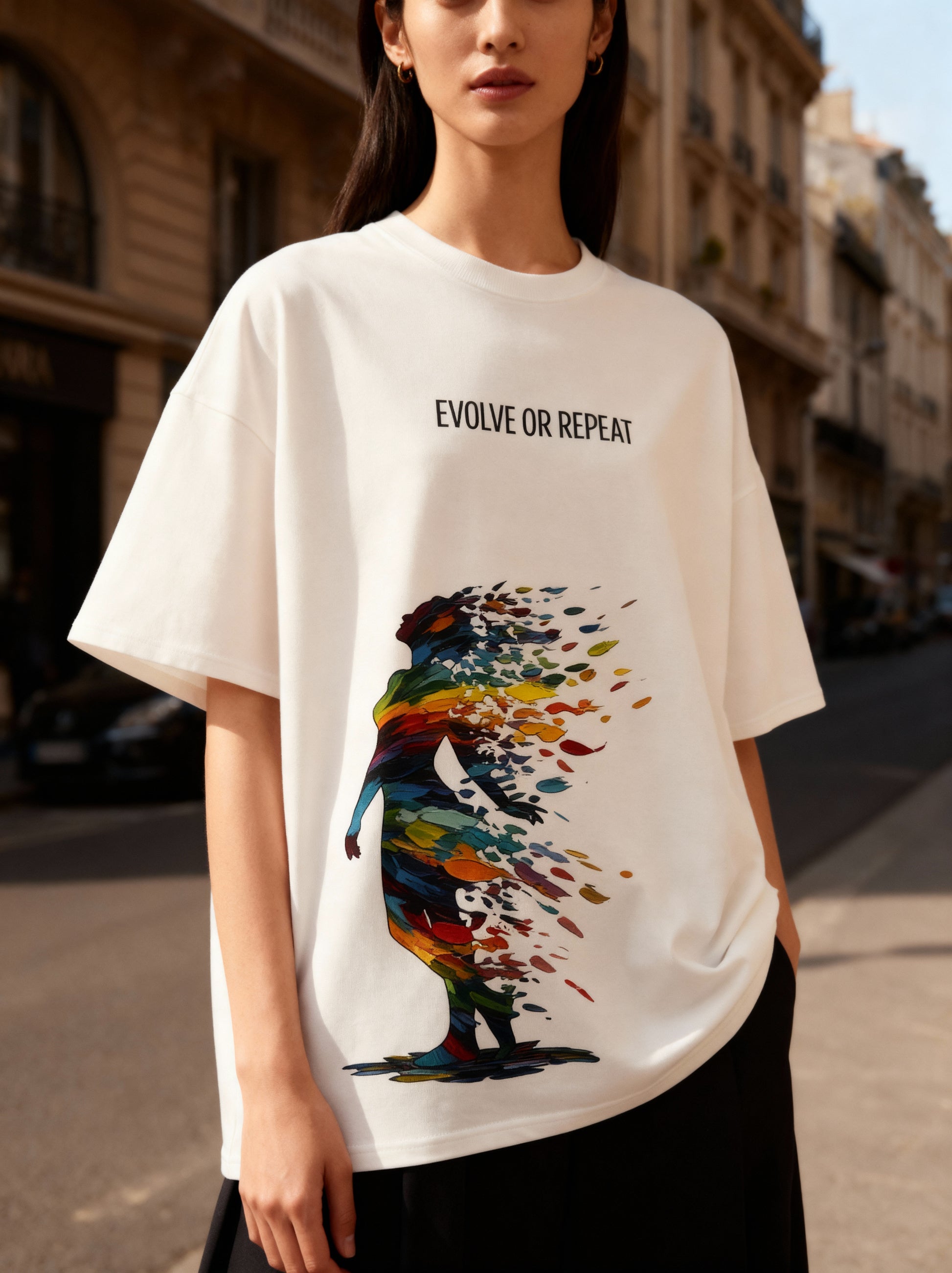 Person wearing a white t-shirt with a colorful graphic and 'Evolve or Repeat' text on a city street.