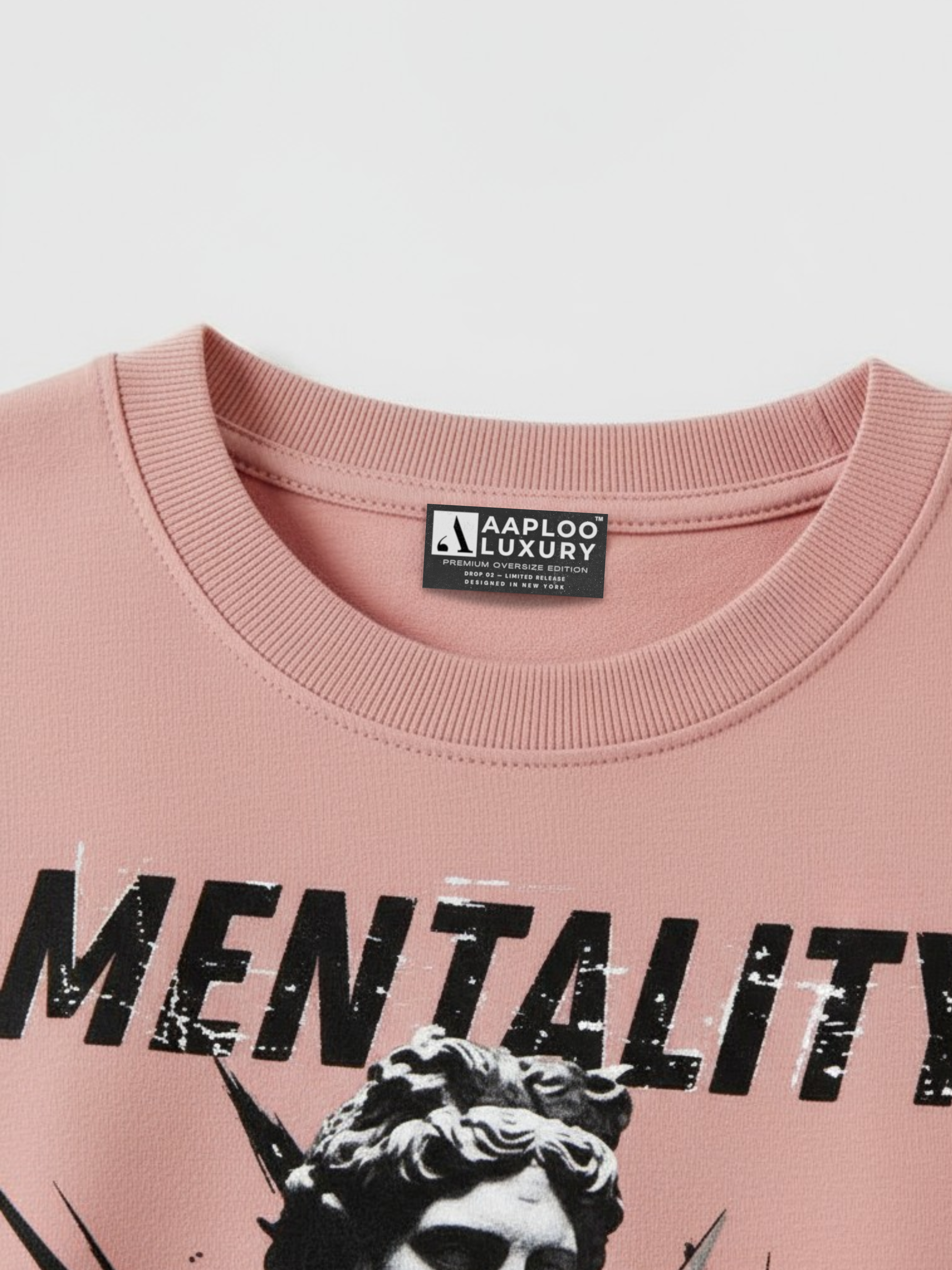 Pink sweatshirt with 'Mentality' text and a brand label on a white background