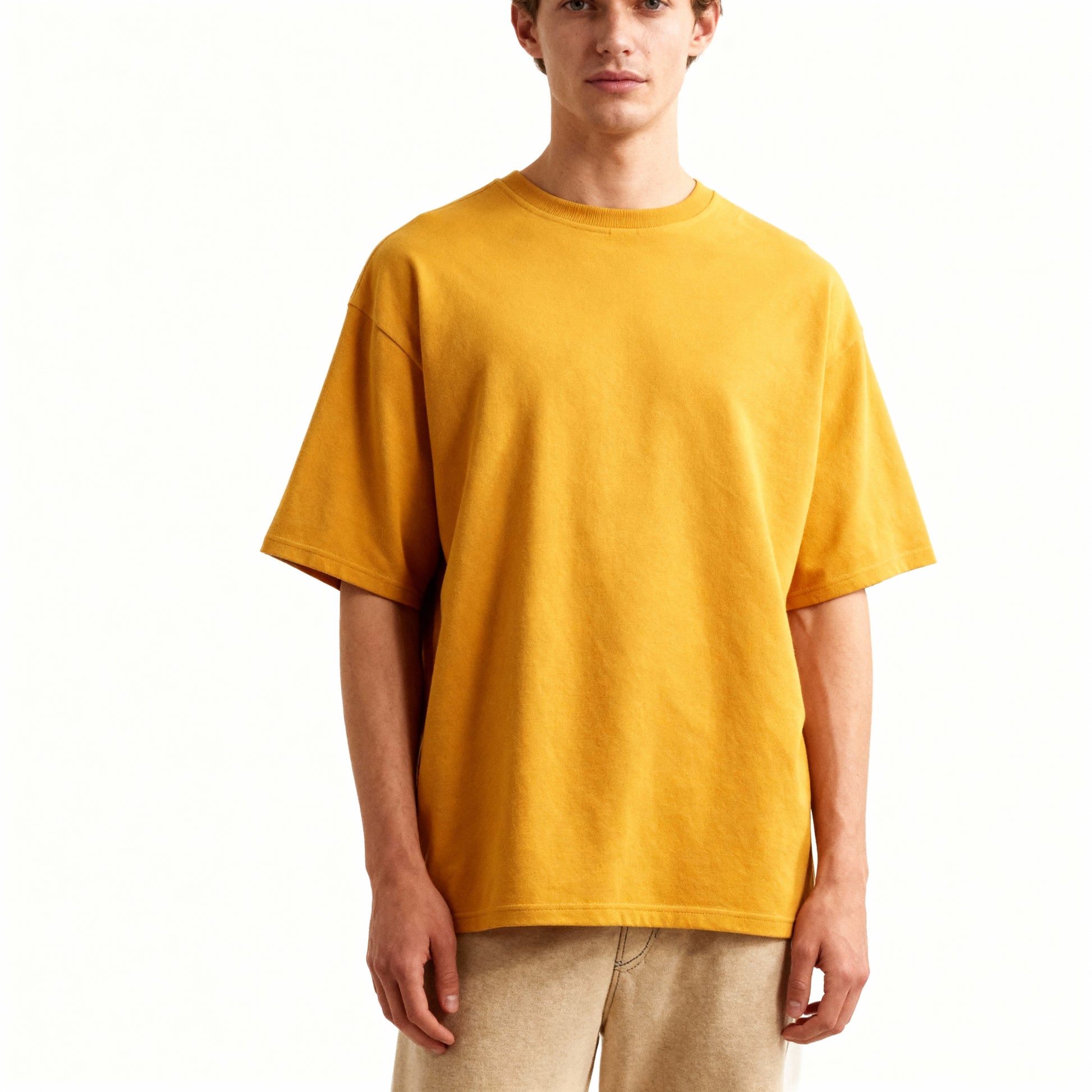 Person wearing a mustard yellow t-shirt on a white background