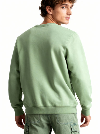 Man wearing a light green sweatshirt and cargo pants on a white background