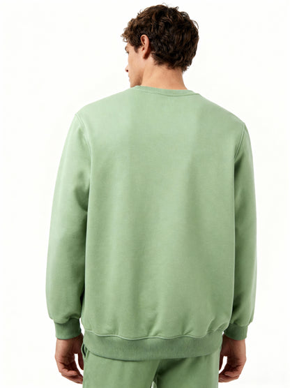 Person wearing a green sweatshirt and pants on a white background