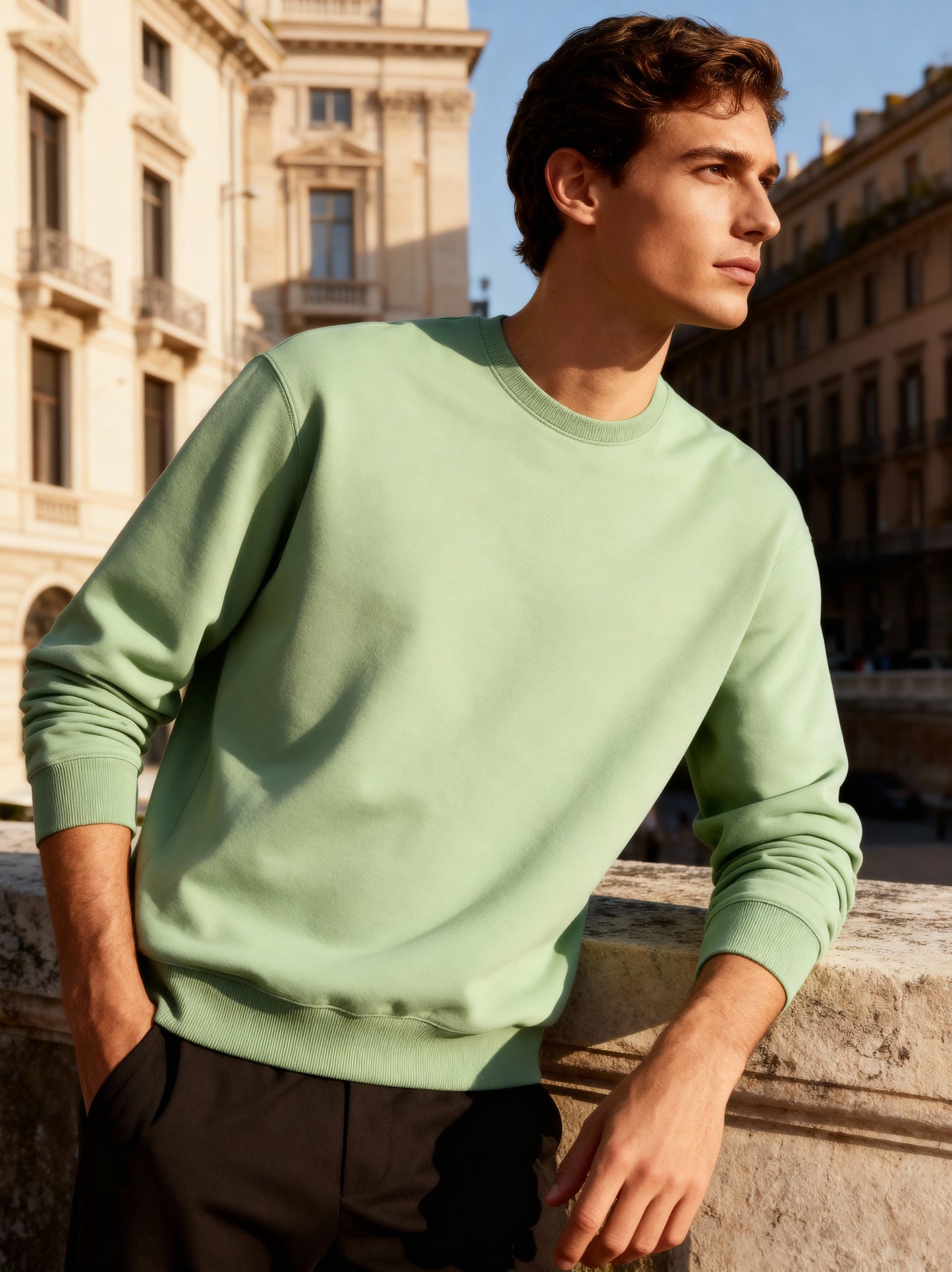Man wearing a light green sweater standing in front of a building