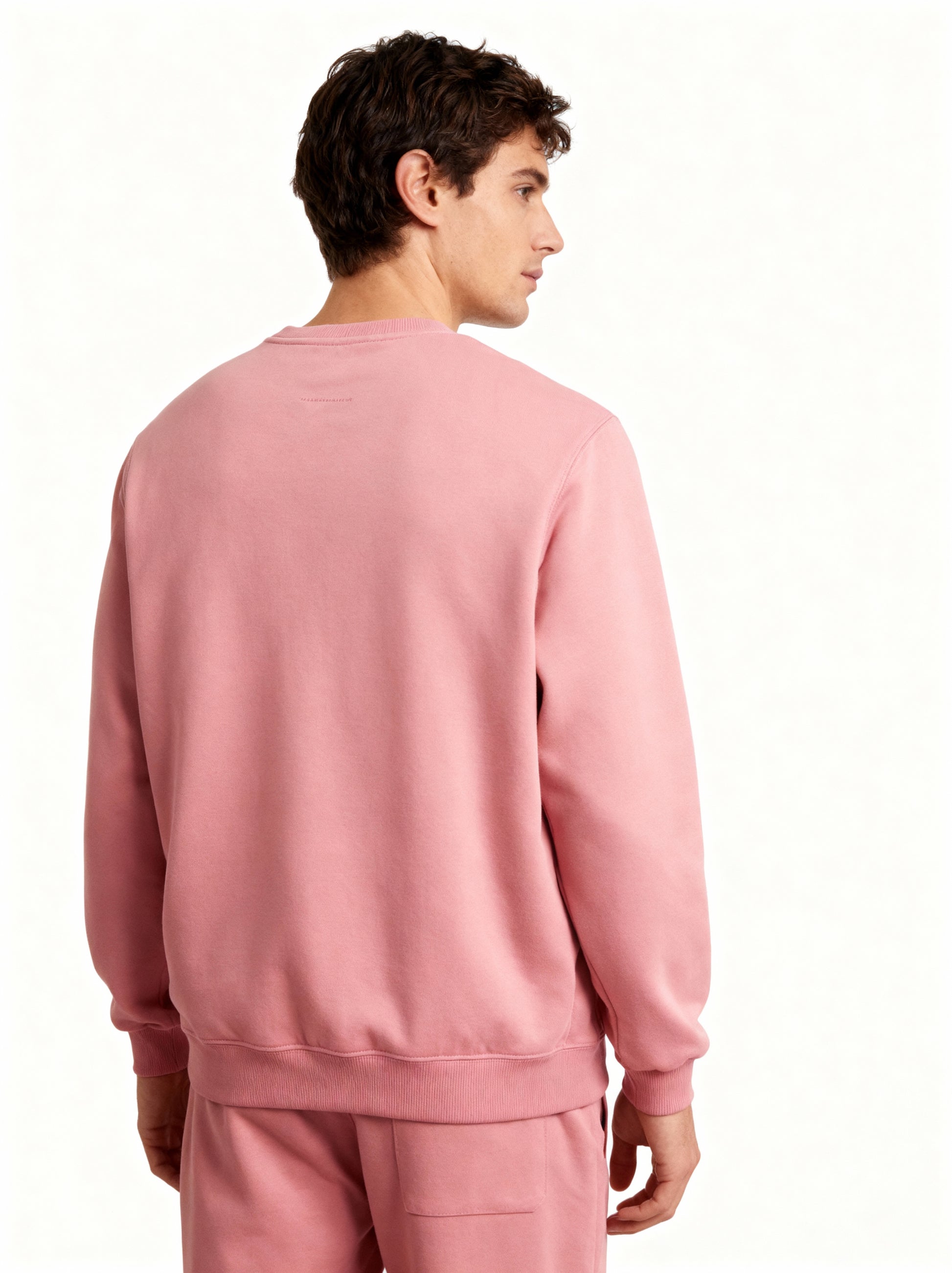 Person wearing a pink sweatshirt and pants on a white background