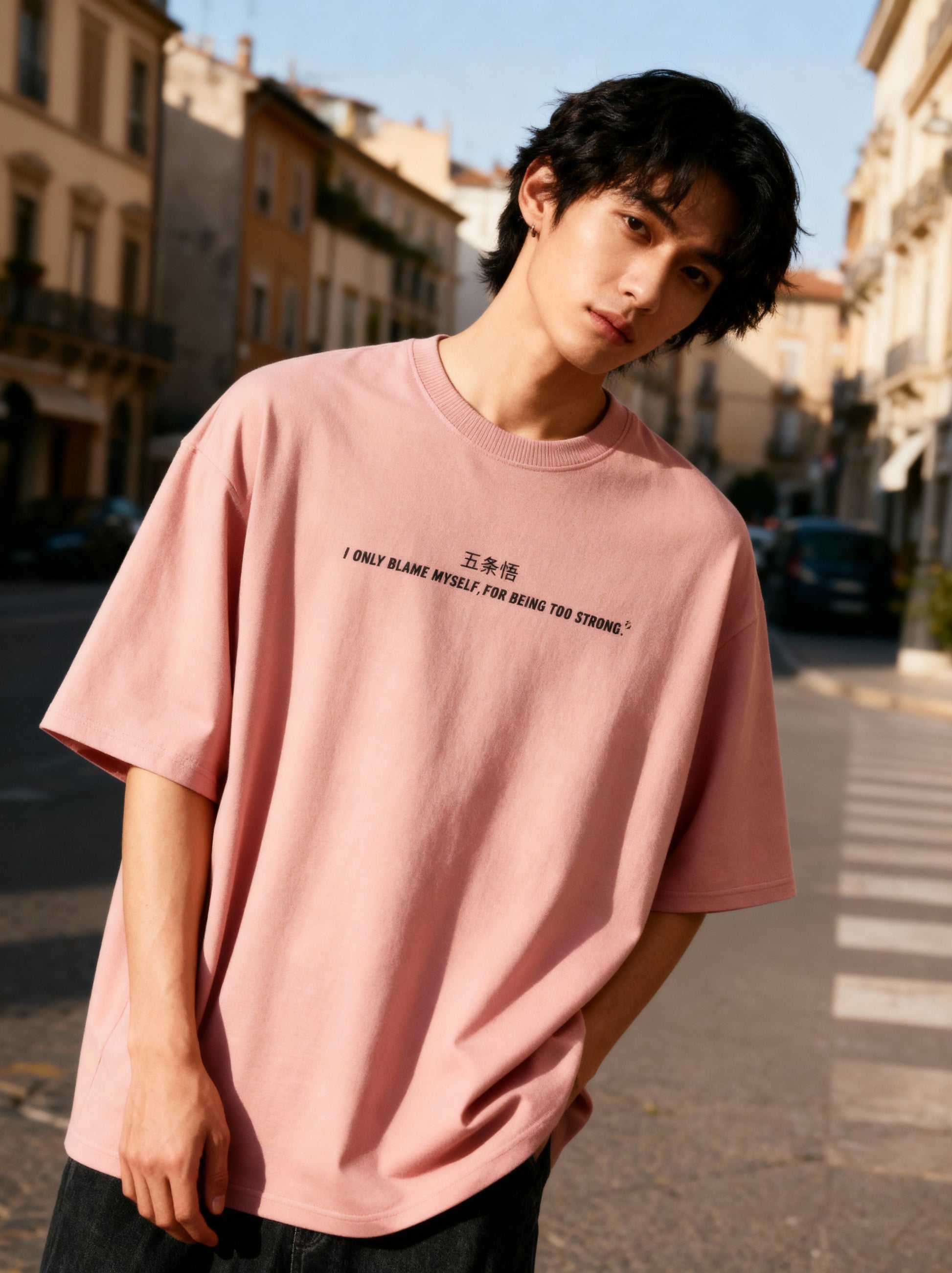 Person wearing a pink t-shirt with text on a city street