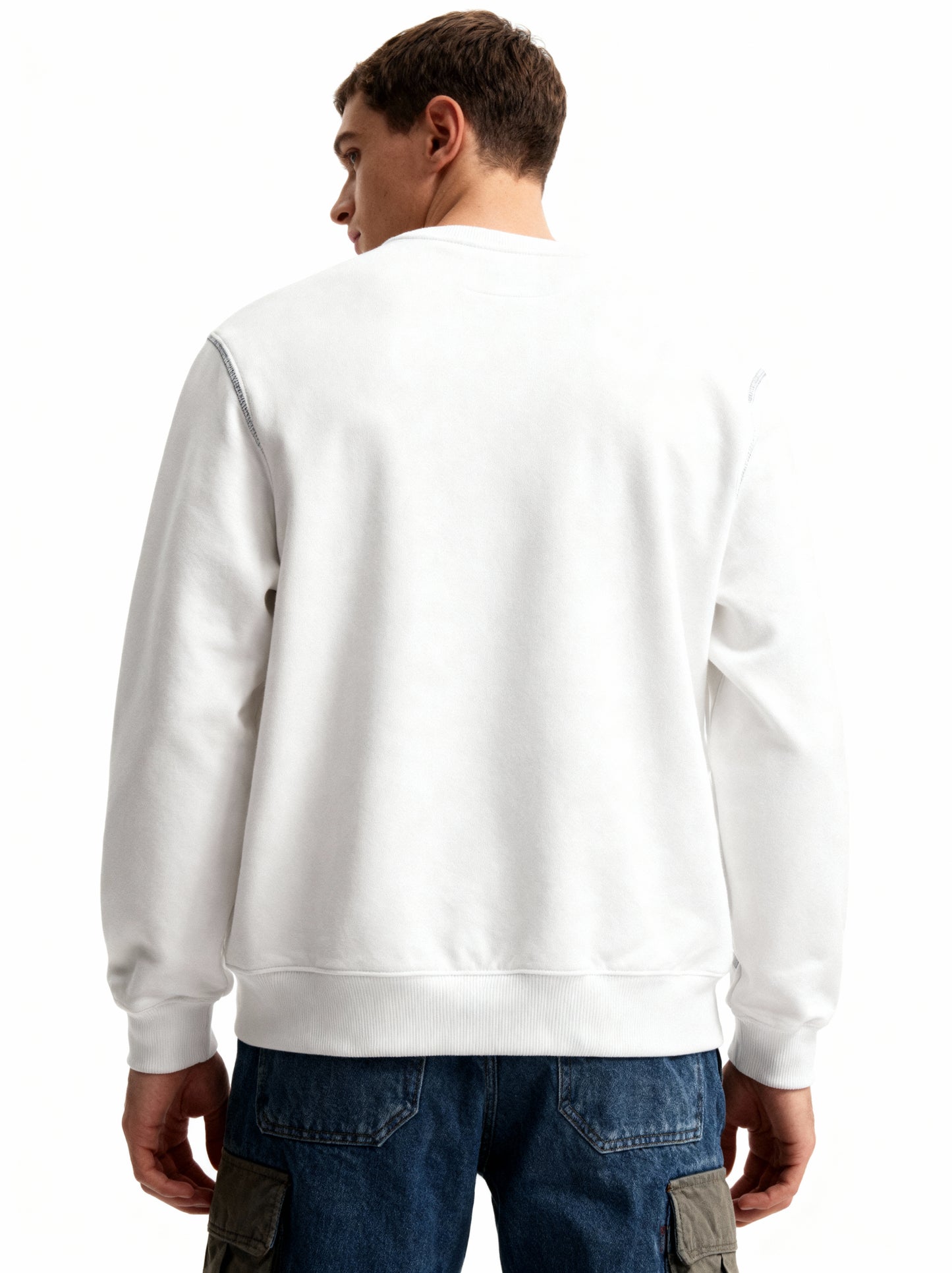 Person wearing a white sweatshirt and blue jeans on a white background