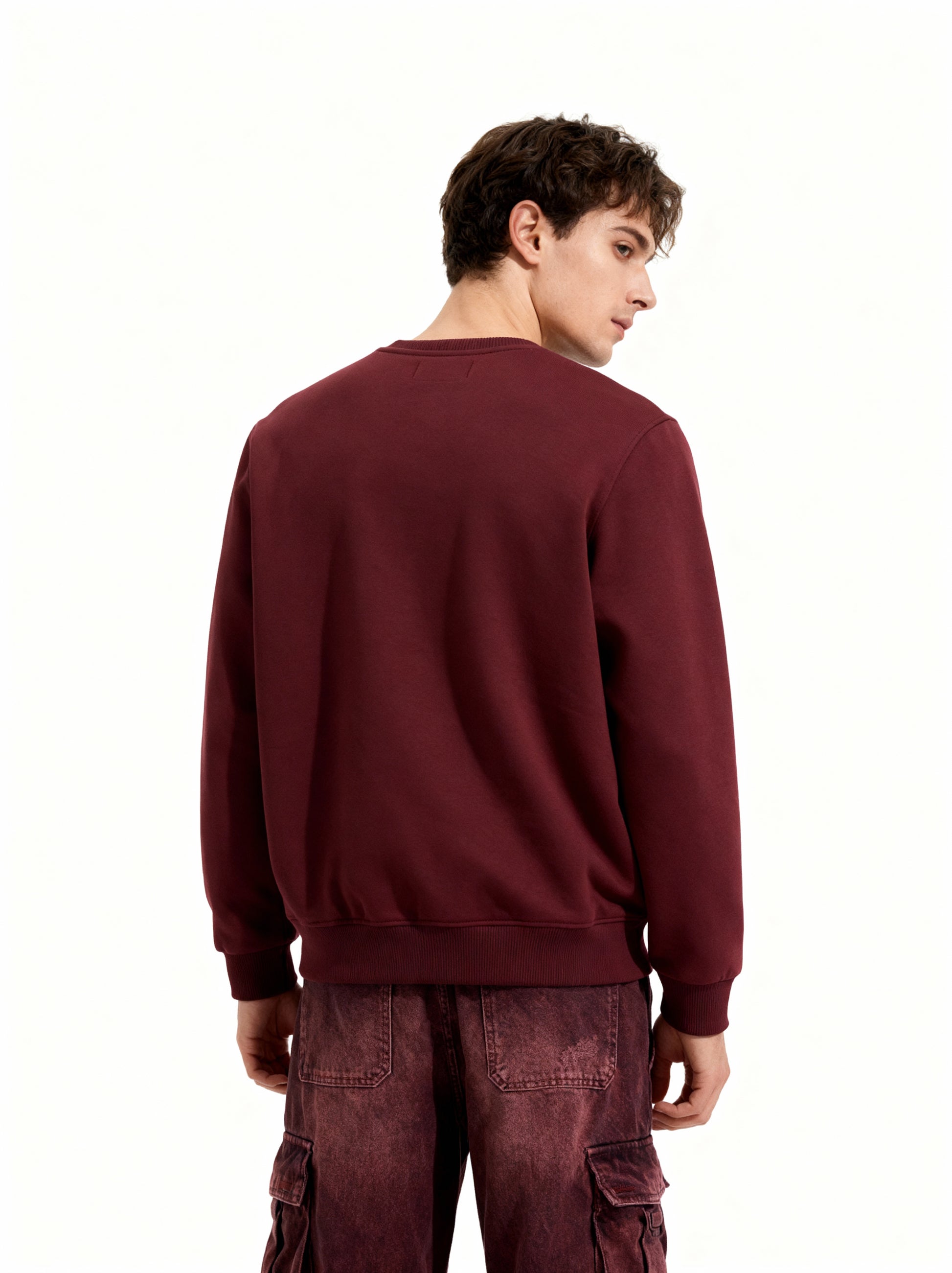 Person wearing a maroon sweatshirt and pants on a white background