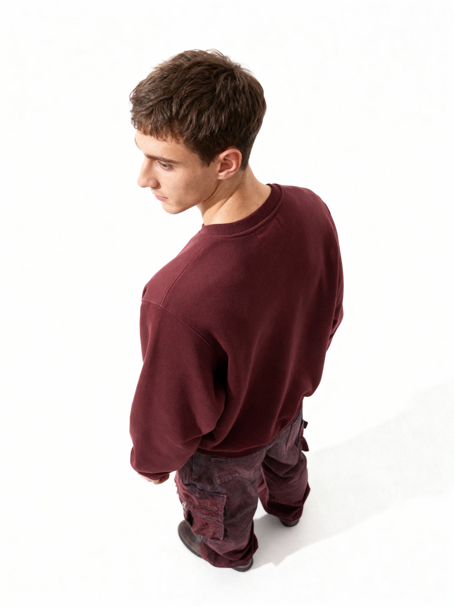 Person wearing a maroon sweatshirt and pants on a white background