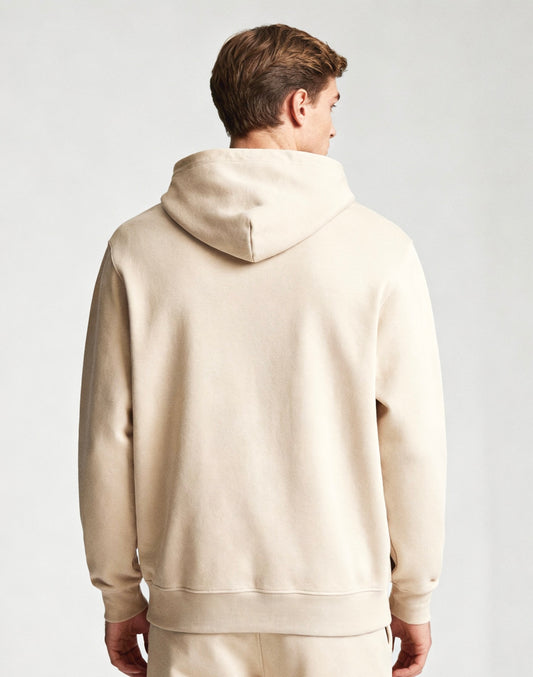 Man wearing a beige hoodie from behind on a light gray background